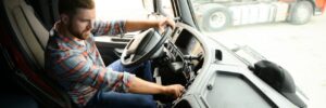 driver behind the wheel in truck cabin.